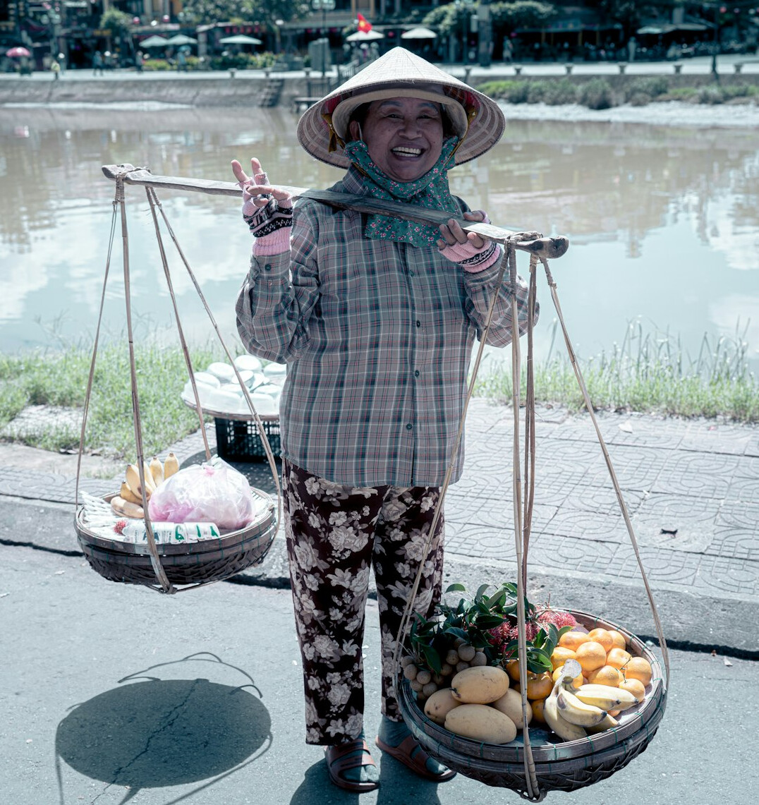 Portrait of an elderly woman with curly gray hair holding a basket of vegetables
